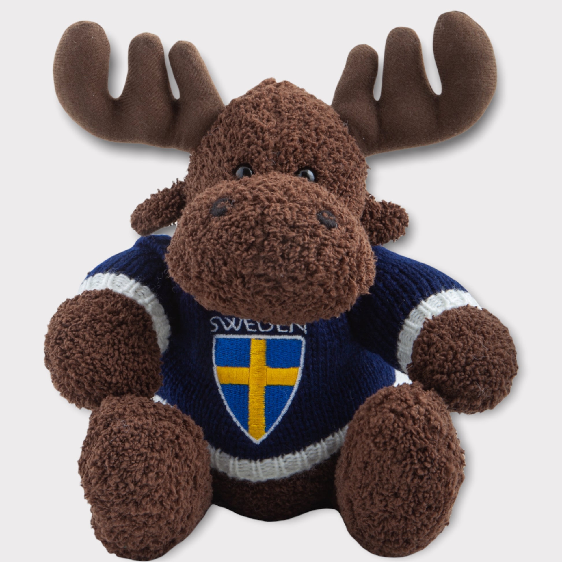 Detaljbild på mjukisälg med stickad Sweden-tröja och broderat märke